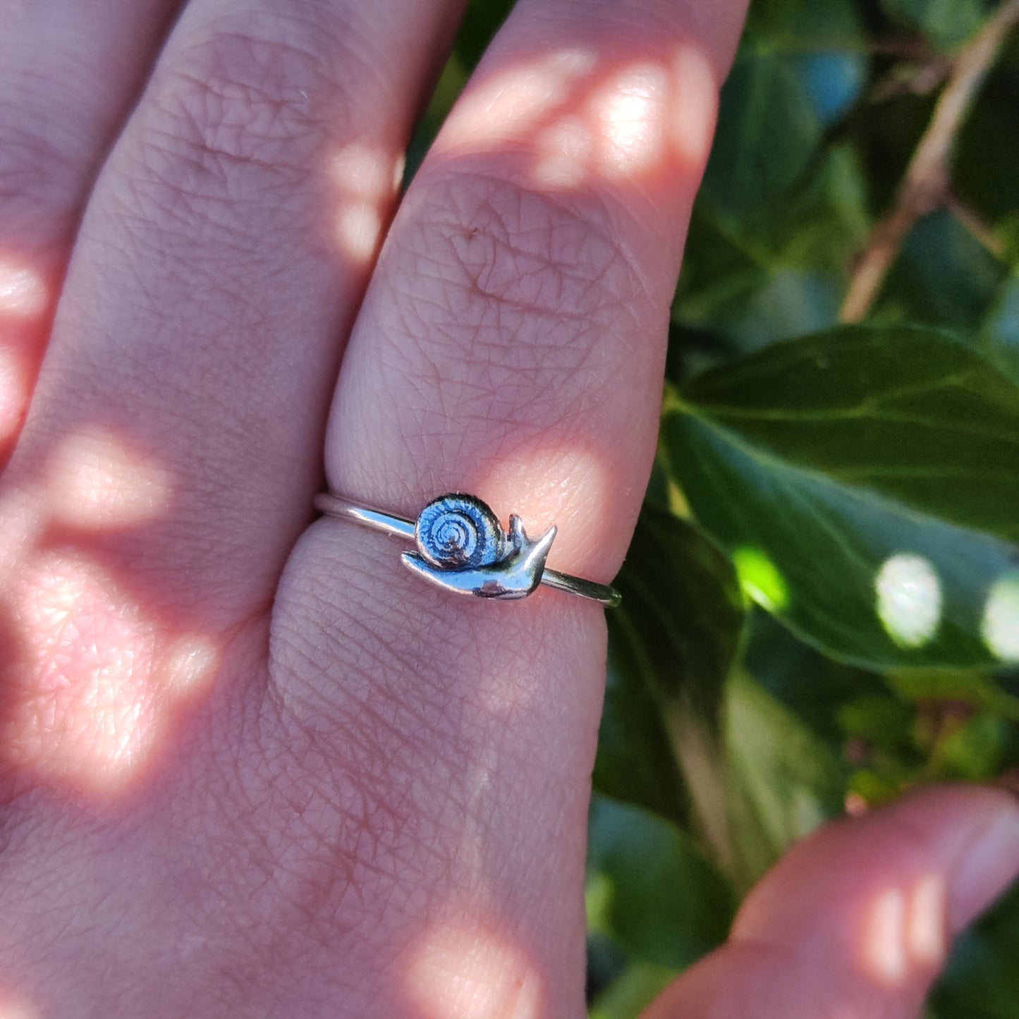 100% Recycled Silver stacker ring featuring a 3D snail being worn on the index finger.