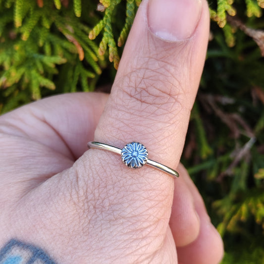 100% Recycled silver stacker ring featuring a daisy motif being worn on the thumb.