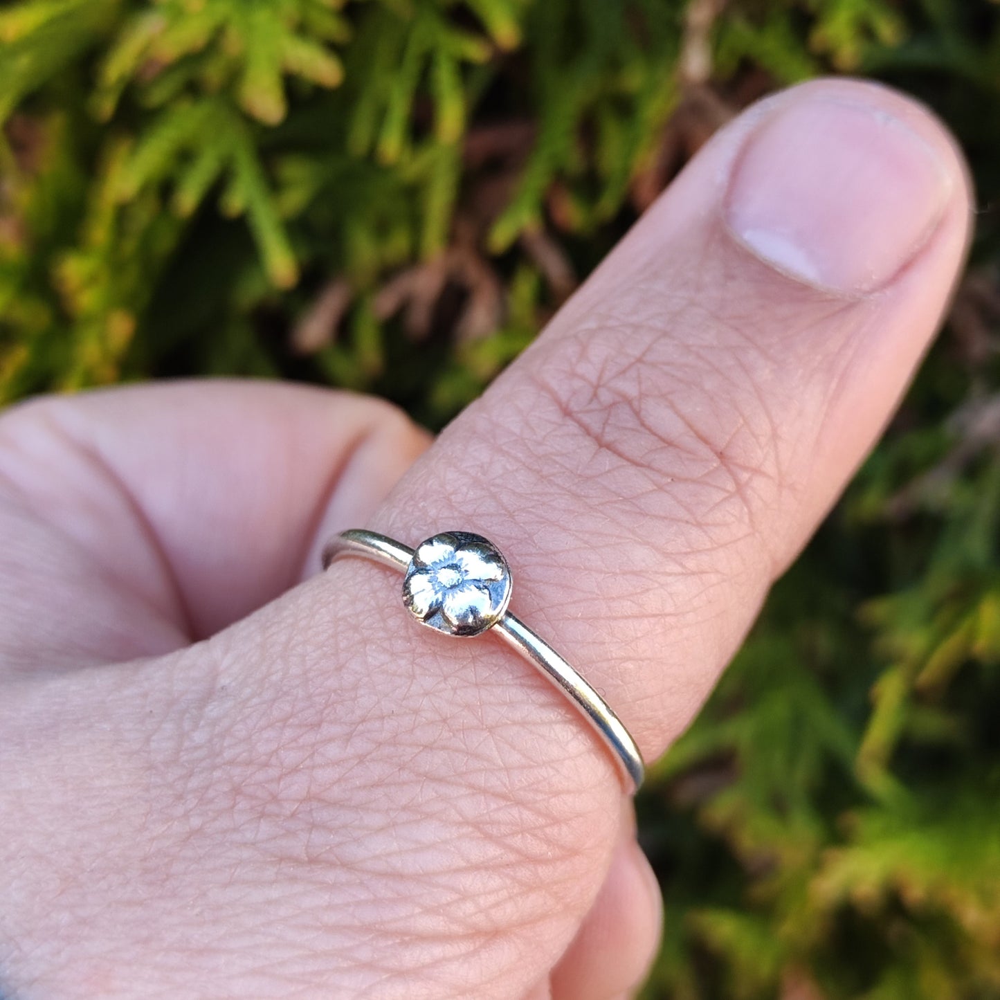 100% recycled silver stacking ring with a medallion flower motif inspired by medieval floral motifs being worn on the thumb.