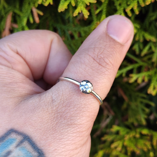 100% recycled silver stacking ring with a medallion flower motif inspired by medieval floral motifs being worn on the thumb.