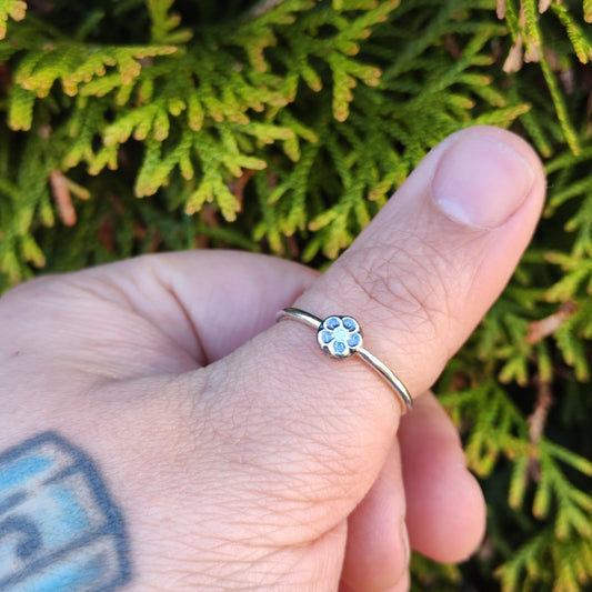 100% recycled silver stacker ring with a 5-petal flower design being worn on the thumb. 
