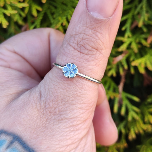 100% recycled silver stacker ring with a 6-petal flower design being worn on the thumb. 