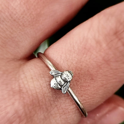 Silver stacking bee ring on a person's finger.